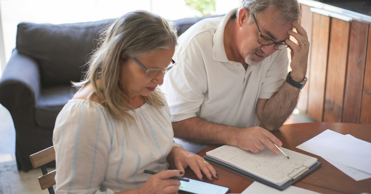 Photo : couple senior examinant des documents et un budget après une hausse de cotisation de mutuelle